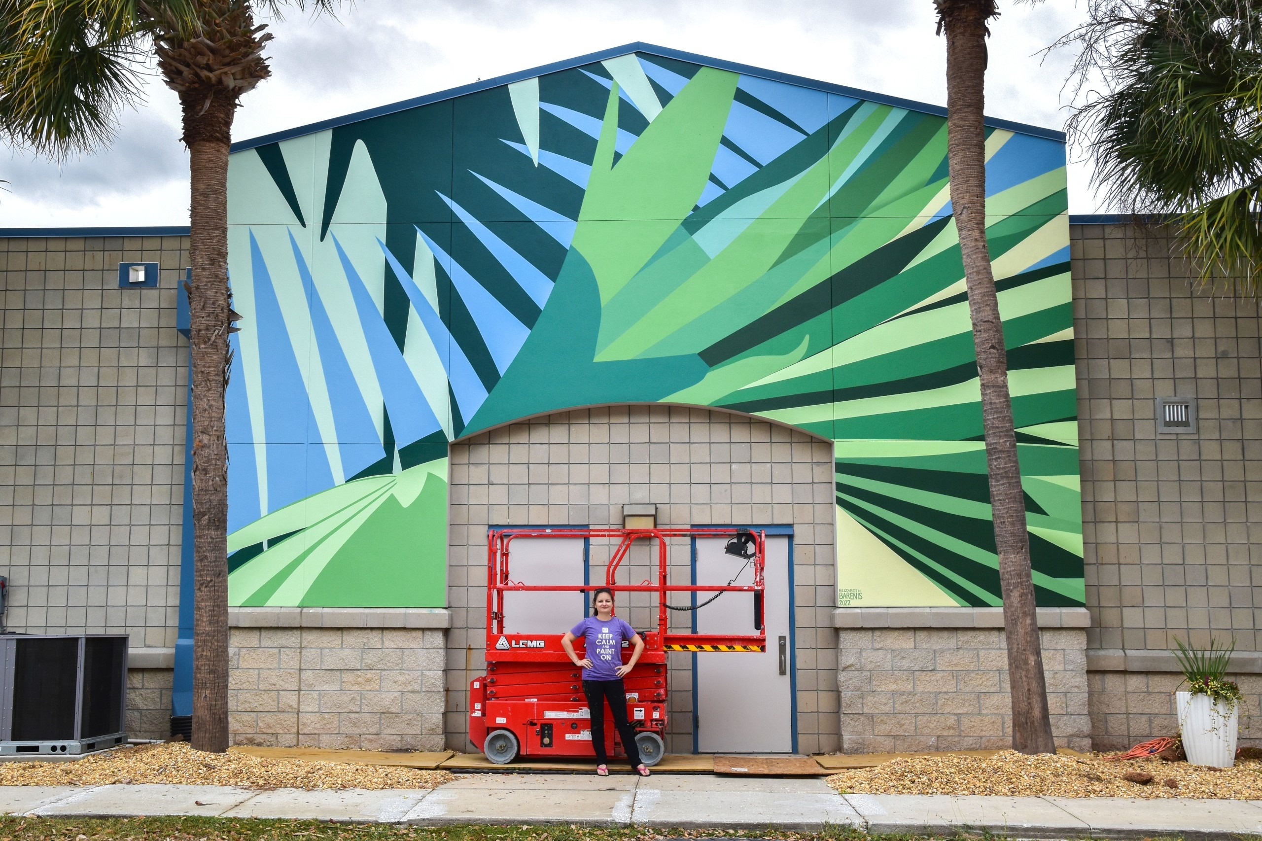 Elizabeth Barenis stands in front of the three hundred square foot mural she completed in November of 2022.