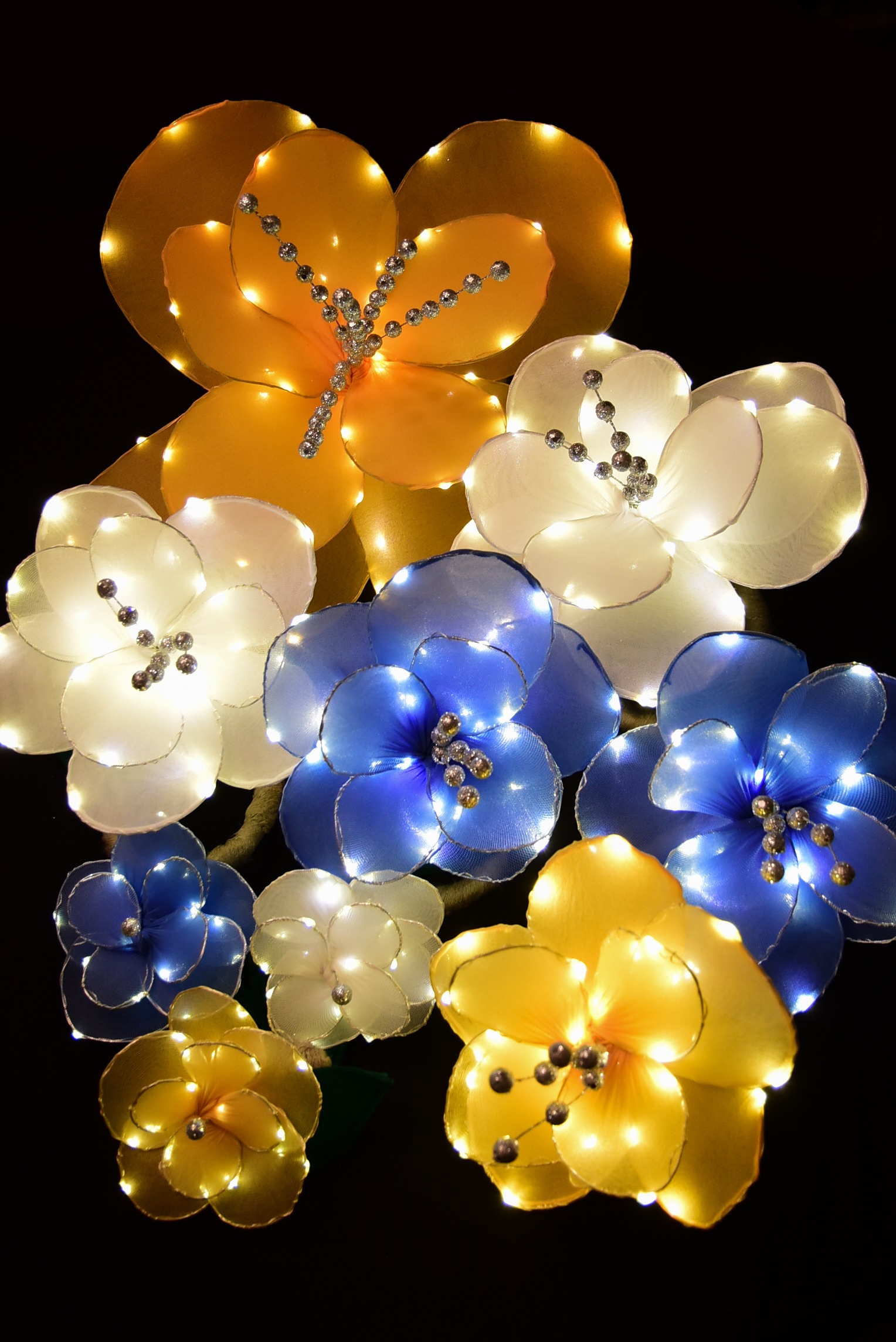 A group of nine light-up flowers is shown. They range in size from five inches to 20 inches, and the colors vary - white, blue, and gold.