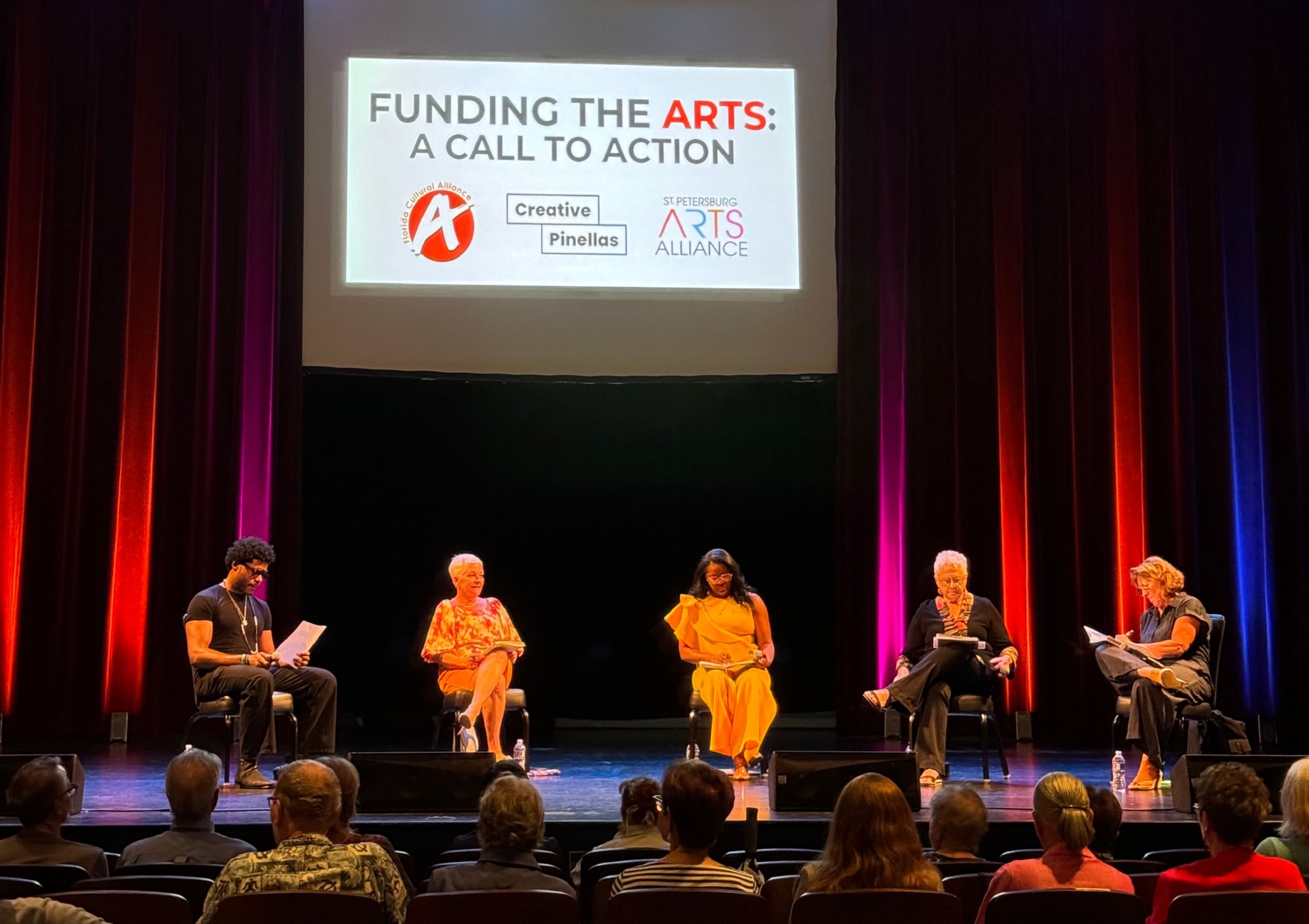 A panel of people sit on a stage.