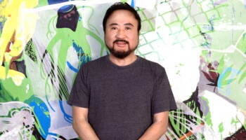 A man poses with a colorful background.