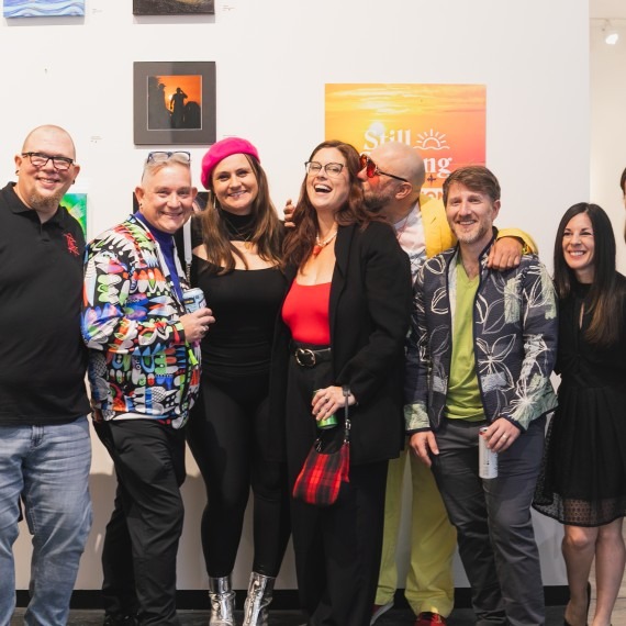 People pose in front of artwork.