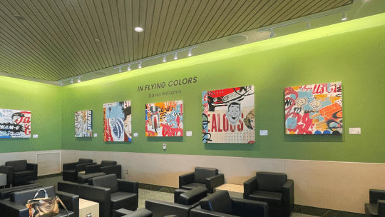 A display of colorful paintings on a green wall.