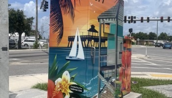 A signal box is decorated with a nautical scene with a sailboat.