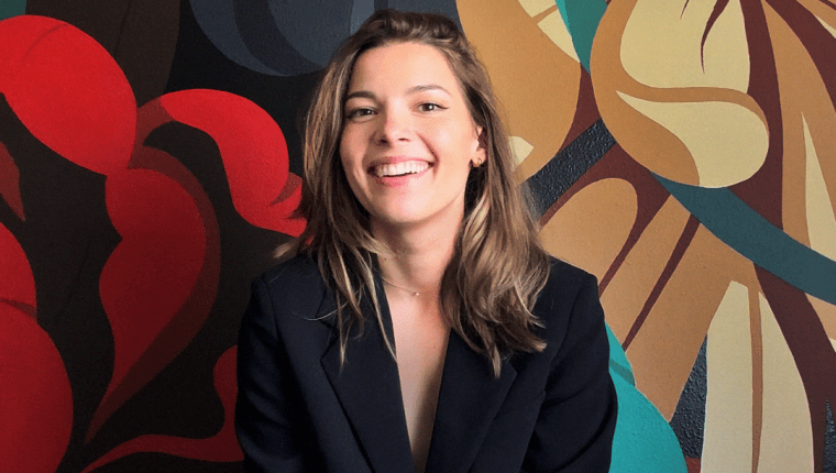 A woman poses with a floral backdrop.