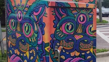 A signal box is decorated with a vibrant cat.
