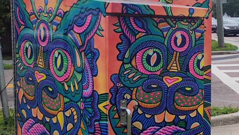 A signal box is decorated with a vibrant cat.